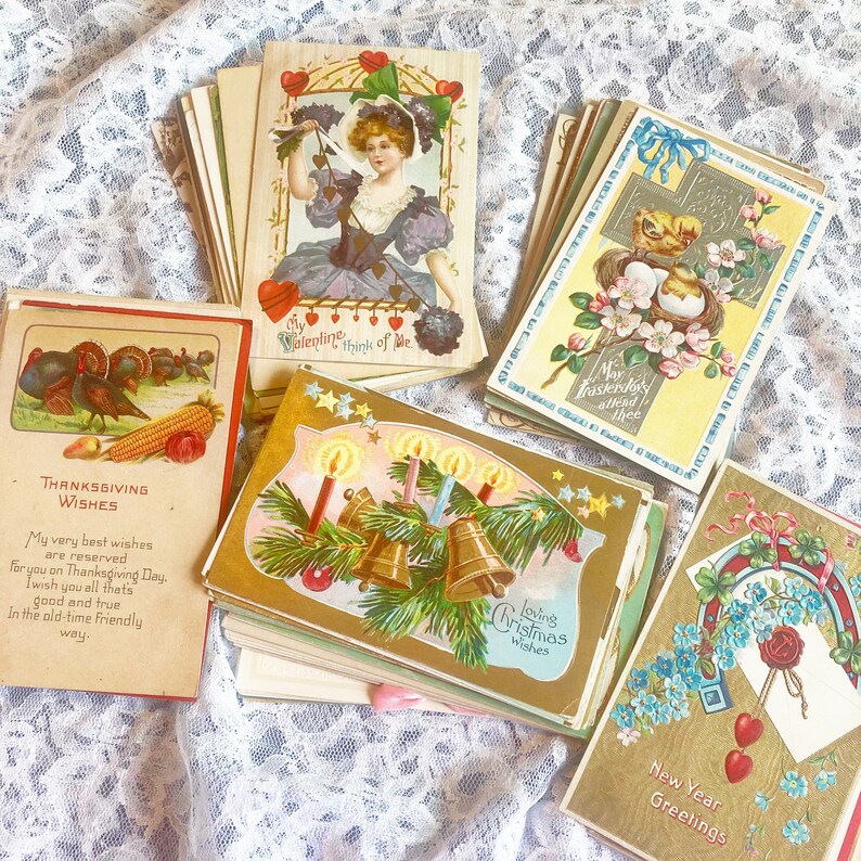 May include: A collection of vintage greeting cards with various holiday themes, including Thanksgiving, Christmas, New Year, and Valentine's Day. The cards feature illustrations, text, and decorative elements.
