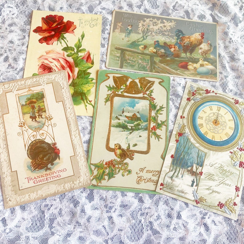 May include: Five vintage postcards with holiday greetings. The postcards feature a turkey, a winter scene with a house, a rooster, a clock, and a rose.