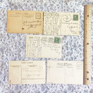 May include: Four vintage postcards with a lace background. The postcards are blank and have a decorative border. The text on the back of the postcards reads "Post Card".
