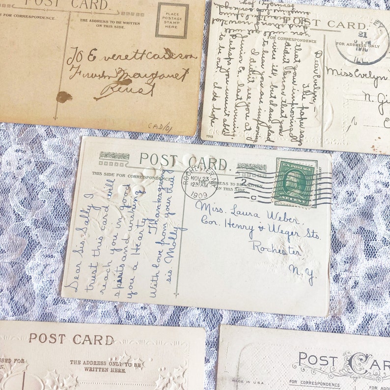 May include: Four vintage postcards with handwritten messages. The postcards are white with a decorative border and the text "Post Card" printed on them. The postcards have a place for a stamp and an address. One postcard has a stamp from November 23, 1909.