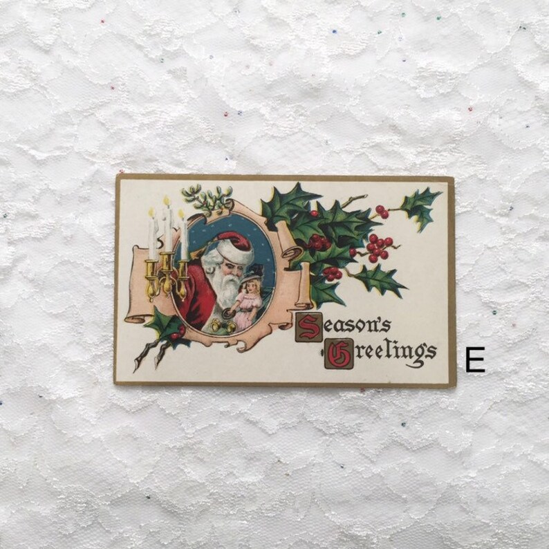 May include: Vintage Christmas postcard featuring a cartoon Santa Claus holding a doll, with candles and holly leaves surrounding him. The text "Season's Greetings" is printed in the bottom right corner.