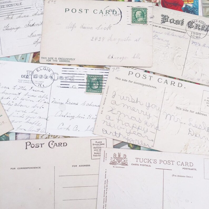 May include: A collection of vintage postcards with handwritten messages. The postcards are in various shades of white and cream with black text. Some of the postcards have stamps and postmarks. The postcards are arranged in a pile.
