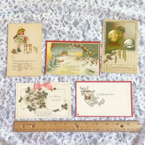 May include: Five vintage holiday greeting cards with various designs. The cards feature a girl with a doll, a winter scene with a house, a chick hatching from an egg, a winter scene with holly and a clock, and a winter scene with holly.