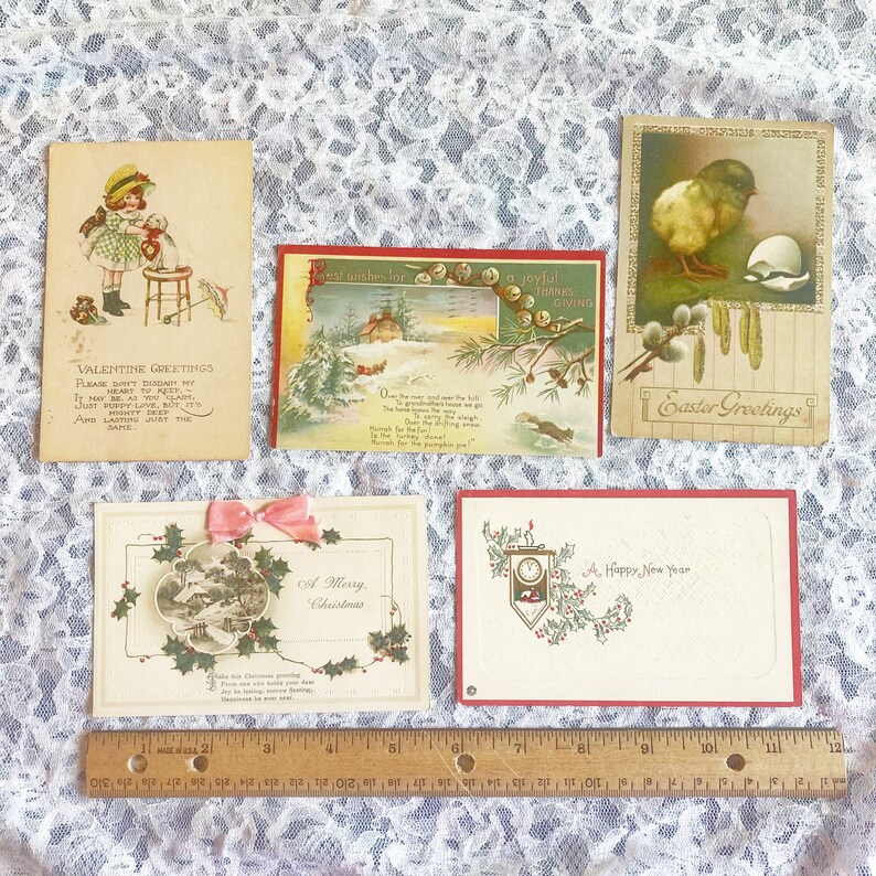 May include: Five vintage holiday greeting cards with various designs. The cards feature a girl with a doll, a winter scene with a house, a chick hatching from an egg, a winter scene with holly and a clock, and a winter scene with holly.