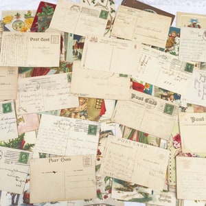 May include: A collection of vintage postcards featuring festive greetings and illustrations. The postcards are in a variety of colours and styles, including red, green, blue, and white. Some of the postcards have handwritten messages on the reverse.