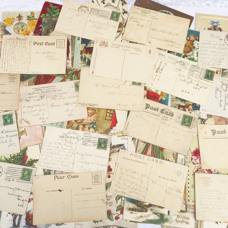 May include: A collection of vintage postcards featuring festive greetings and illustrations. The postcards are in a variety of colours and styles, including red, green, blue, and white. Some of the postcards have handwritten messages on the reverse.