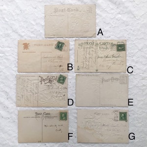 May include: Seven vintage postcards with embossed floral designs. Each postcard has a space for a message and a stamp. The postcards are in various shades of cream and white.