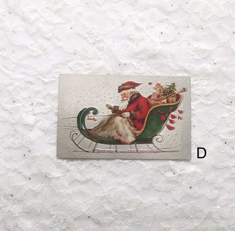 May include: Vintage Christmas postcard featuring a red-suited Santa Claus riding in a green sleigh with a small elf. The postcard has a white background with a dotted pattern and the text "Merry Xmas".