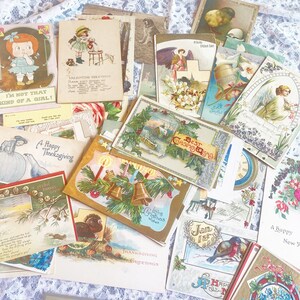 May include: A collection of vintage postcards featuring various holiday themes, including Christmas, Thanksgiving, and New Year's. The postcards are decorated with festive illustrations, such as holly, bells, and snowflakes. Some of the postcards have handwritten messages.