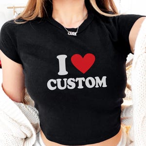 May include: Black crop top with the text "I ♥ CUSTOM" in white and a red heart. The shirt has short sleeves and a crew neck. The top is made of a soft material.