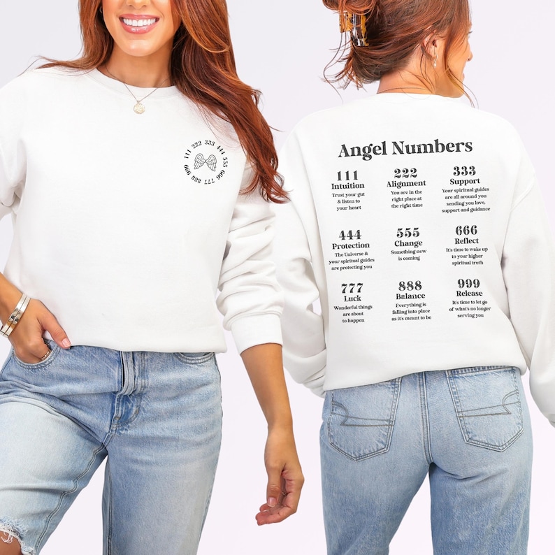 May include: White sweatshirt with the text "Angel Numbers" on the back and a small graphic on the front. The back of the sweatshirt lists angel numbers with their meanings. The model is wearing blue jeans.