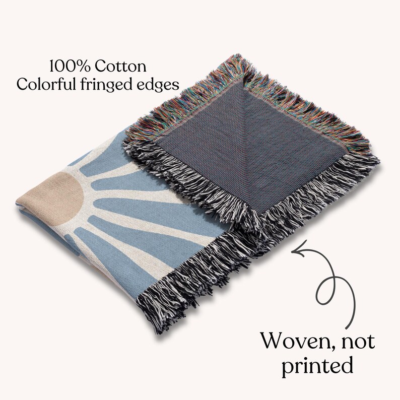 May include: A woven cotton throw blanket with a blue and beige sunburst design. The blanket has colorful fringed edges and the text "Woven, not printed". The blanket is made of 100% cotton.