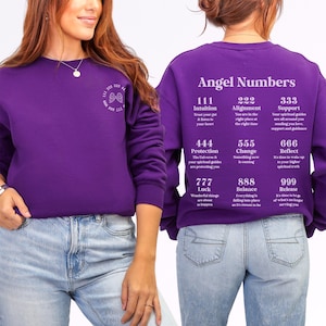 May include: A purple sweatshirt with the words "Angel Numbers" printed on the back. The sweatshirt features a list of angel numbers and their meanings. The front of the sweatshirt has a small design with the numbers 222, 333, and 444.