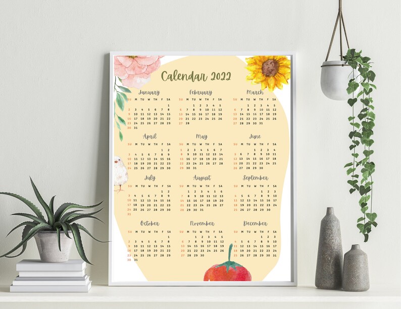 May include: A printable calendar for 2022 with a yellow background and watercolor illustrations of flowers, a sunflower, a bird, and a tomato. The months are listed in a grid format with the days of the week labeled.
