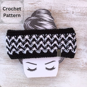 Può includere: Fascia per capelli in crochet bianco e nero con un motivo geometrico. La fascia è su un manichino con uno chignon.