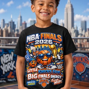 Puede incluir: Una camiseta negra con un diseño gráfico colorido que presenta una pelota de baloncesto con gafas de sol, un trofeo y el texto "NBA FINALS 2026". La camiseta también incluye las palabras "Little Knicks Fan", "Big Finals Energy" y "Future MVP!"