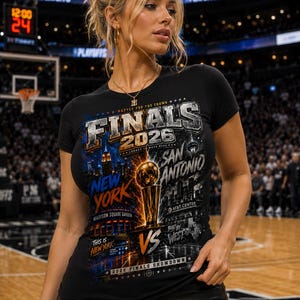 May include: A black short-sleeved t-shirt featuring a graphic print that reads Finals 2026, New York, San Antonio, Madison Square Garden, AT&T Center, This is New York, Built by West, and 2026 Finals Showdown, with a central gold basketball trophy.