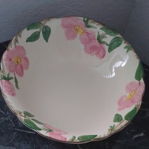 May include: A white ceramic bowl with a scalloped edge and a floral design featuring pink roses and green leaves.