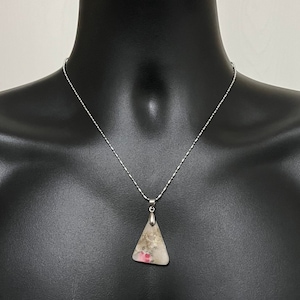 May include: A silver chain necklace with a triangular pendant made of clear, white, and pink stone. The pendant has a silver bail.