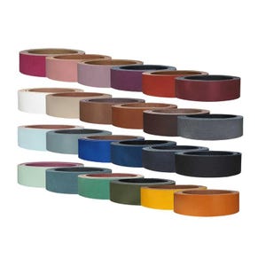 May include: A collection of twenty-four leather strips arranged in four rows, featuring a diverse palette of colors including shades of red, pink, purple, brown, white, beige, blue, gray, black, green, yellow, and orange in a circular coil.