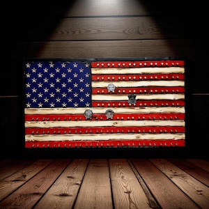 May include: Wooden American flag with red and white stripes and a blue field of stars. The flag has a black frame and is decorated with several metal pins and badges. The flag is displayed on a wooden wall.