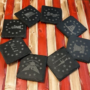 May include: Set of ten black slate coasters with various patriotic designs, including stars, an eagle, a liberty bell, a rifle, and the words "Come and Take It".