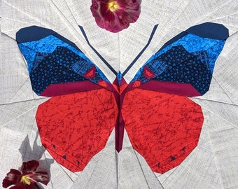 May include: A fabric butterfly quilt block with red, blue, and burgundy wings, set against a white background. The wings have detailed patterns. Two flowers are placed near the quilt. The text "Sewn by @off.kilter.quilter" is at the top.
