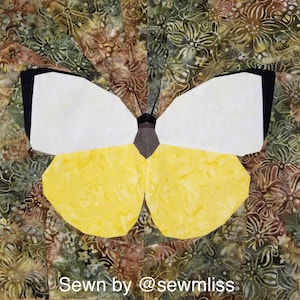May include: A fabric butterfly quilt block with white and yellow wings, black accents, and a brown body. The background features a batik fabric with green, brown, and cream floral patterns. Text at the bottom reads "Sewn by @sewmliss."