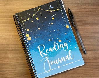 May include: A blue and black spiral bound journal with a watercolour background and gold stars. The cover reads "Reading Journal" in white cursive lettering.
