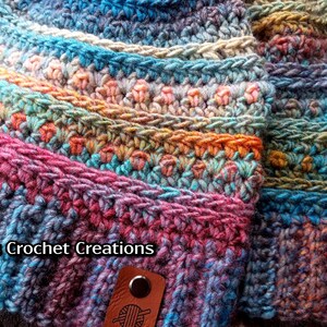 Pu&ograve; includere: Due cappelli all'uncinetto colorati con filato multicolore. I cappelli sono realizzati con diversi punti e motivi. I cappelli hanno un'etichetta in pelle marrone con un gomitolo di lana e il testo "Nana's Crochet Creations".