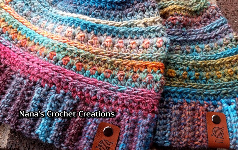 Pu&ograve; includere: Due cappelli all'uncinetto colorati con filato multicolore. I cappelli sono realizzati con diversi punti e motivi. I cappelli hanno un'etichetta in pelle marrone con un gomitolo di lana e il testo "Nana's Crochet Creations".