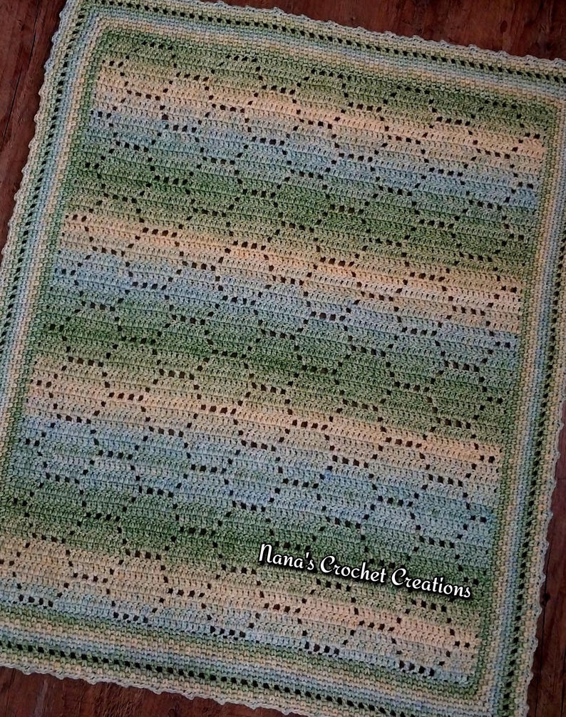 May include: A rectangular crochet blanket featuring a repeating geometric pattern in variegated shades of green, blue, and cream. The blanket has a decorative scalloped border and includes the text Nana's Crochet Creations in the lower right corner.