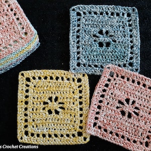 Op de afbeelding: Vier gehaakte vierkanten in verschillende kleuren: roze, blauw, geel en een stapel roze en blauwe vierkanten. De vierkanten hebben een kantpatroon met een centrale open ruimte.