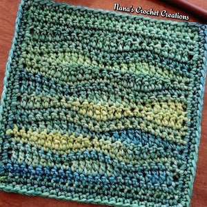 Puede incluir: Un paño de ganchillo cuadrado y hecho a mano en tonos verdes, azules y amarillos. El paño presenta un patrón de puntadas texturizadas y un borde sólido. El texto "Nana's Crochet Creations" es visible en la esquina superior derecha.