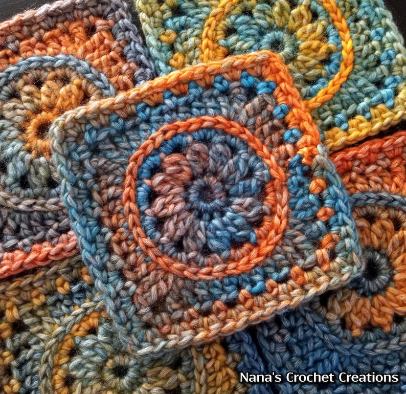 May include: Close-up of colorful crocheted squares with a circular pattern in the center. The squares are made with a variety of shades of blue, orange, and brown yarn.