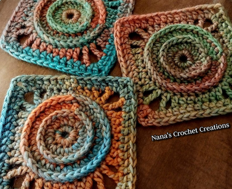 May include: Three crocheted squares with a multi-colored, circular pattern in shades of blue, green, orange, and brown. The squares are made with a textured stitch and have a lacy appearance. The text "Nana's Crochet Creations" is visible in the bottom right corner of the image.