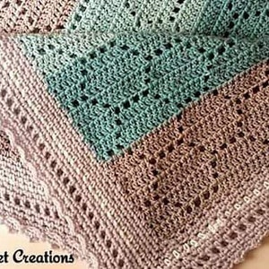 May include: A crocheted blanket featuring a color-blocked design in soft beige and teal. The textile displays an intricate openwork pattern with a scalloped border edge. The text Nana's Crochet Creations is printed in the bottom left corner.