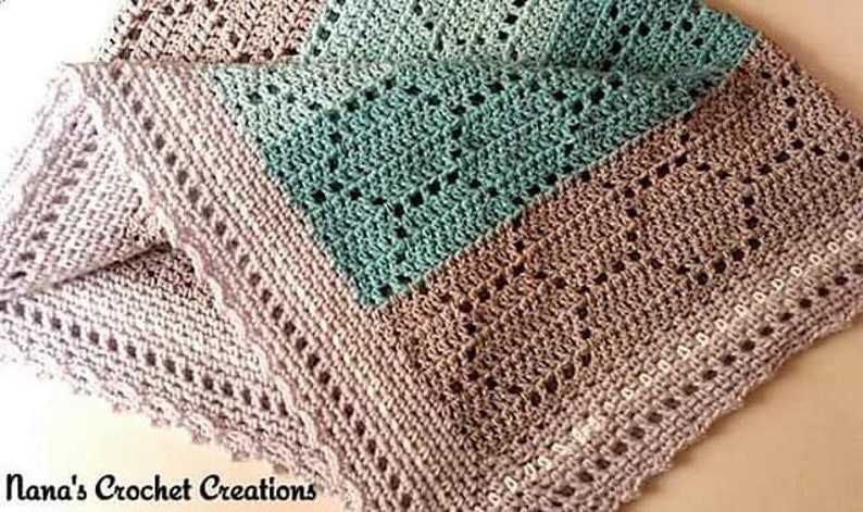 May include: A crocheted blanket featuring a color-blocked design in soft beige and teal. The textile displays an intricate openwork pattern with a scalloped border edge. The text Nana's Crochet Creations is printed in the bottom left corner.