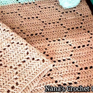 May include: A beige crochet blanket featuring a repeating hexagonal pattern with openwork stitches. The blanket has a light mint green border at the top edge. The text Nana's Crochet Creations is printed in the bottom right corner of the image.