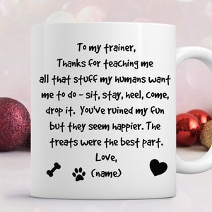 Puede incluir: Taza de caf&eacute; de cer&aacute;mica blanca con una huella de pata negra y un dise&ntilde;o de hueso. La taza tiene un mensaje de texto negro que dice "To my trainer, Thanks for teaching me all that stuff my humans want me to do - sit, stay, heel, come, drop it. You've ruined my fun but they seem happier. The treats were the best part. Love, (name)"