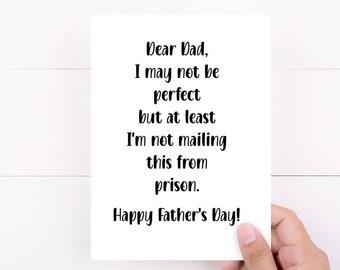 May include: A white rectangular greeting card with black printed text that reads: Dear Dad, I may not be perfect but at least I'm not mailing this from prison. Happy Father's Day! The card features a simple, clean design with bold, dark lettering.