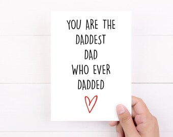 May include: A white rectangular greeting card featuring black text that reads YOU ARE THE DADDEST DAD WHO EVER DADDED, positioned above a simple, hand-drawn red heart outline. The card has a clean, minimalist design with bold, sans-serif lettering.