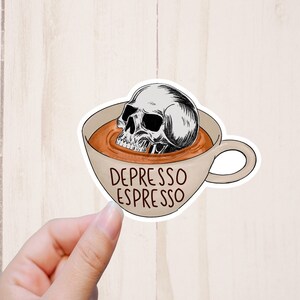 May include: A white coffee cup with a skull inside and brown liquid. The text 
