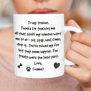 a white coffee mug with black text that says thank you to a dog trainer in funny ways.  The trainer's name can be added, along with the dog's name.