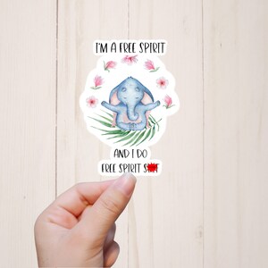 May include: A sticker with a blue elephant meditating with pink flowers around it. The text on the sticker reads "I'm a free spirit and I do free spirit shit."