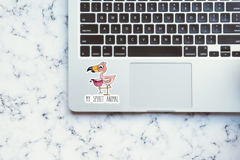 May include: A pink flamingo with a glass of wine in its hand, with the text "MY SPIRIT ANIMAL" below it. The sticker is on a silver laptop.