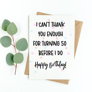 Może przedstawiać: Biała kartka urodzinowa z napisem "I can't thank you enough for turning 50 before I do. Happy Birthday!". Kartka ma kolorowe kropki i jest połączona z brązową kopertą i liśćmi eukaliptusa.