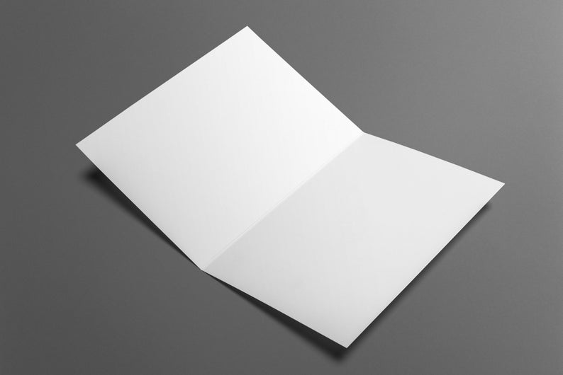Op de afbeelding: Een opengevouwen witte kaart ligt op een grijze ondergrond. De kaart is in een hoek geplaatst, waardoor de binnenkant en de scherpe randen van het papier zichtbaar zijn. Geschikt voor uitnodigingen.
