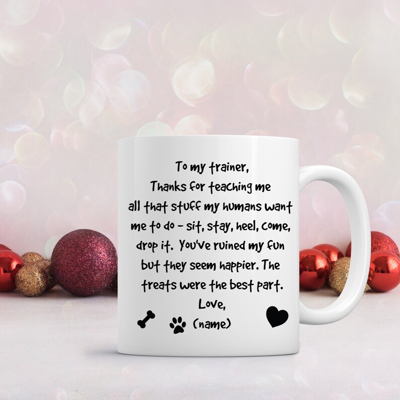 Puede incluir: Taza de caf&eacute; de cer&aacute;mica blanca con una huella de pata negra y un dise&ntilde;o de hueso. La taza tiene un mensaje de texto negro que dice "To my trainer, Thanks for teaching me all that stuff my humans want me to do - sit, stay, heel, come, drop it. You've ruined my fun but they seem happier. The treats were the best part. Love, (name)"
