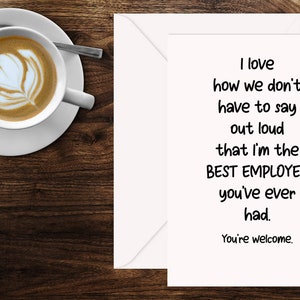 May include: A white greeting card with black text that reads: I love how we don't have to say out loud that I'm the BEST EMPLOYEE you've ever had. You're welcome. The card is placed next to a white envelope and a white ceramic cup of coffee.